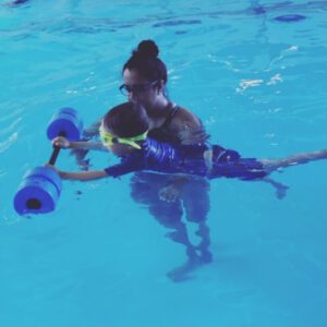 Child receiving personalized swimming instruction with floatation aids in a pool, emphasizing Aqua Life Swim Academy's focus on individualized attention and skill development.