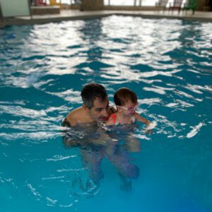 Instructor and child enjoying swimming lesson in Aqua Life Swim Academy's pool, emphasizing personalized instruction and engagement.
