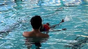 Instructor assisting child in swimming lesson at Aqua Life Swim Academy, showcasing personalized coaching in a pool setting.