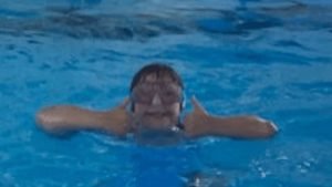 Happy child in swimming pool giving thumbs up, showcasing enjoyment of swimming lessons at Aqua Life Swim Academy.